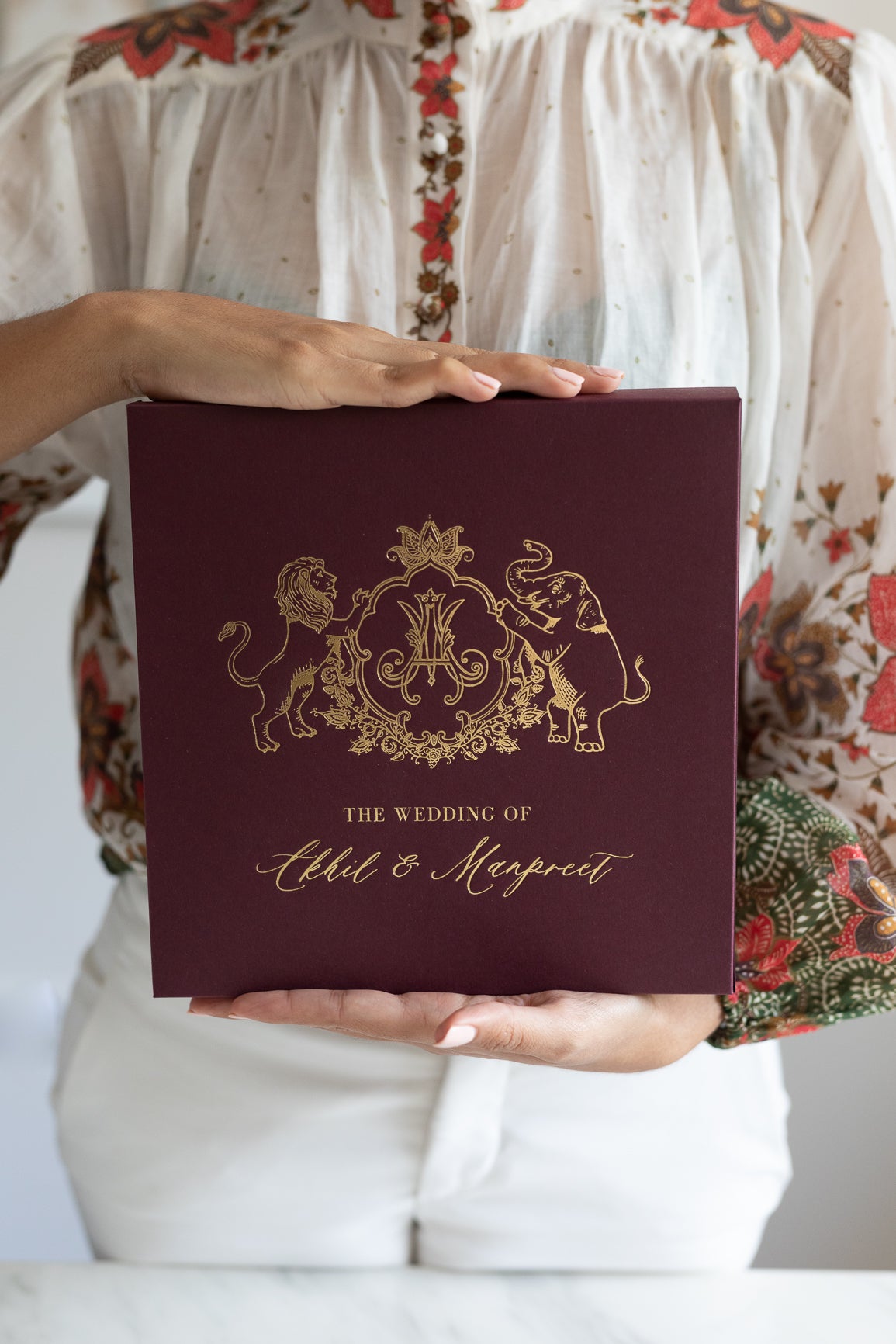 Burgundy and gold Indian wedding invitation with regal wedding crest